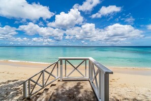 A beach with a wooden walkway leading to the water, clear skies, and a calm sea. - Clearwater 4 Bedroom Home (Gibbes)