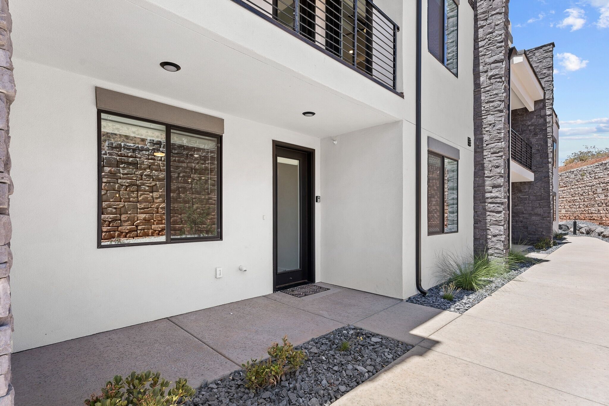 A modern two-story building with a stone facade, large windows, and a clean, minimalist design.