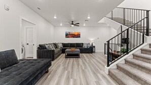 Una sala moderna con un sofá seccional, una mesa de centro y una escalera con barandilla.