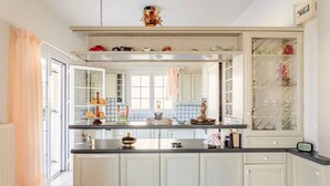 A kitchen with a central island, white cabinetry, and a glass-fronted display cabinet. - Casa Nebari Seaside Home-fully Equipped Ideal Spot (Messini)