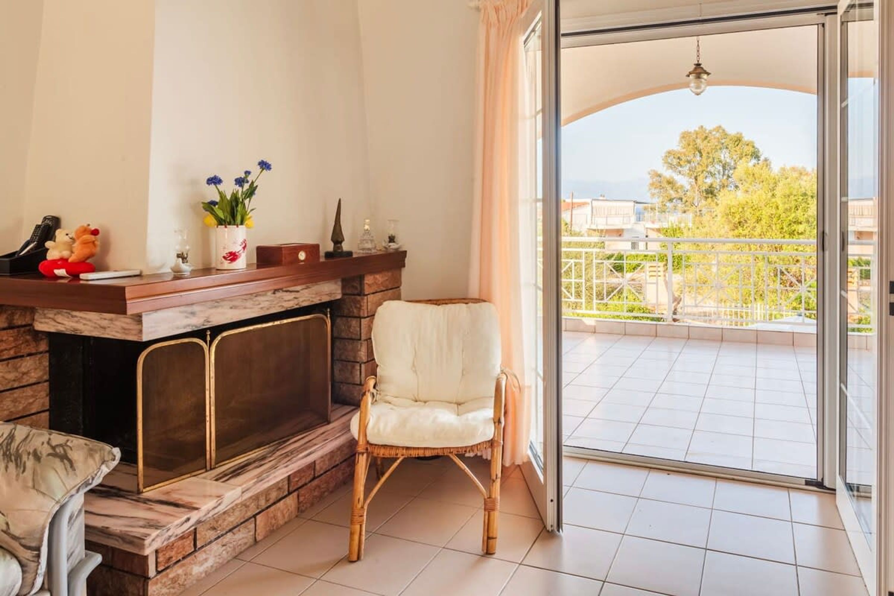Una sala de estar con chimenea, un sillón blanco y vistas a un balcón con barandilla.