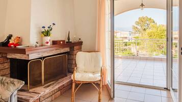 Una sala de estar con chimenea, un sillón blanco y vistas a un balcón con barandilla.