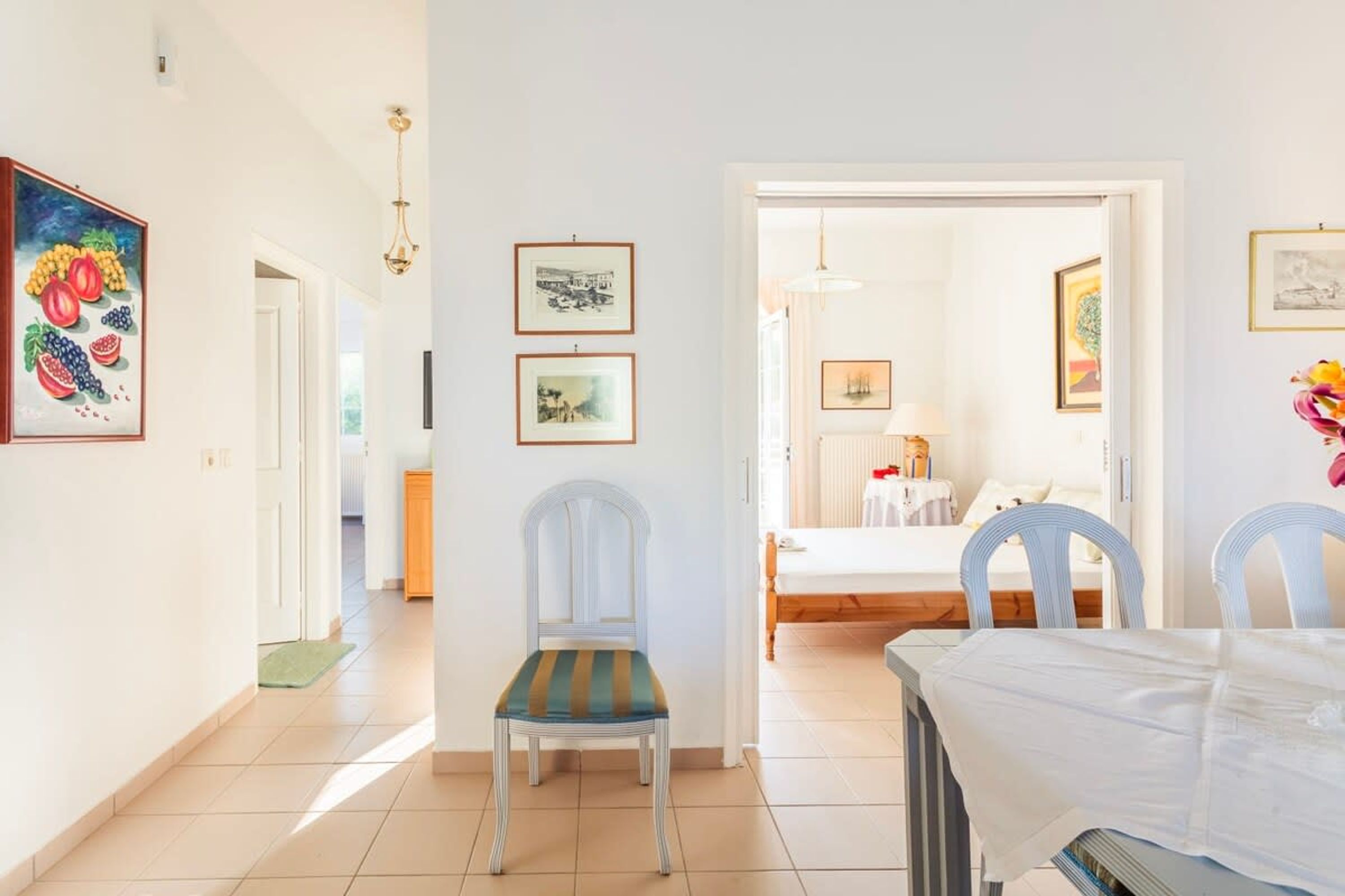 A hotel room with a bed, a dining table, and chairs. There are framed pictures on the walls.