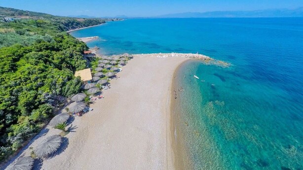 An aerial view of a beach with clear blue waters, a sandy shore, and lush greenery. - Casa Nebari Seaside Home-fully Equipped Ideal Spot (Messini)