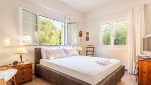 A bedroom with a large bed, two bedside tables with lamps, a wooden dresser, and a window with curtains. - Casa Nebari Seaside Home-fully Equipped Ideal Spot (Messini)