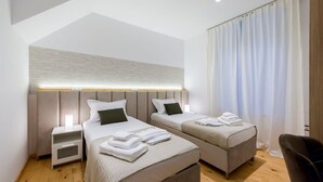 A modern hotel room with two beds, a nightstand, a chair, and a large window with curtains. - Aigli Seafront Loft-bespoke Design Gem (Kalamata)