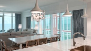 Une cuisine moderne dotée d’un grand îlot central, de luminaires suspendus et offrant une vue sur la ville grâce à de grandes fenêtres.