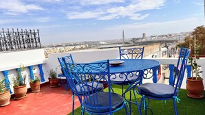 A rooftop terrace with blue metal furniture, potted plants, and a view of the cityscape. - Charming Riad la perle des Oudayas - Rabat (Rabat)