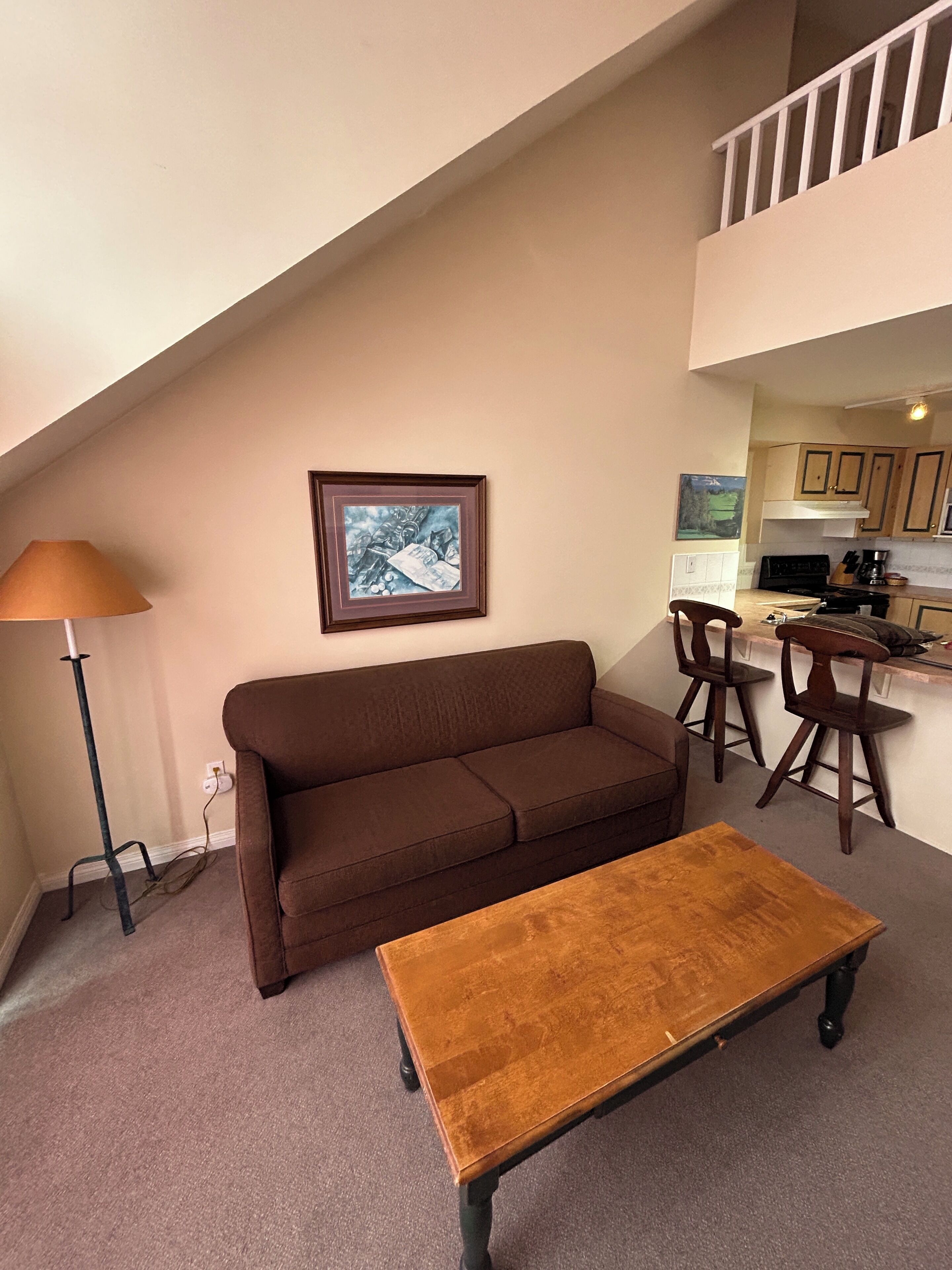 A living room with a brown sofa, a wooden coffee table, a lamp, and a framed picture on the wall.
