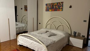 A bedroom with a bed, nightstand, and a mirror.