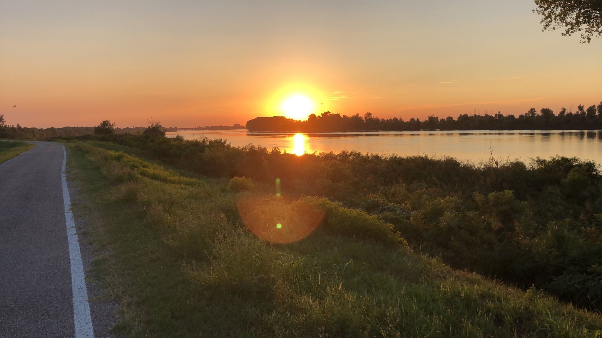 A road leading to a body of water with a sunset in the background.