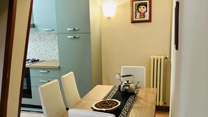 A dining area with a wooden table, white chairs, a decorative tray, and a wall-mounted light fixture.