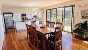 A modern kitchen with white cabinets, a stainless steel refrigerator, and a dining area with a wooden table and chairs.