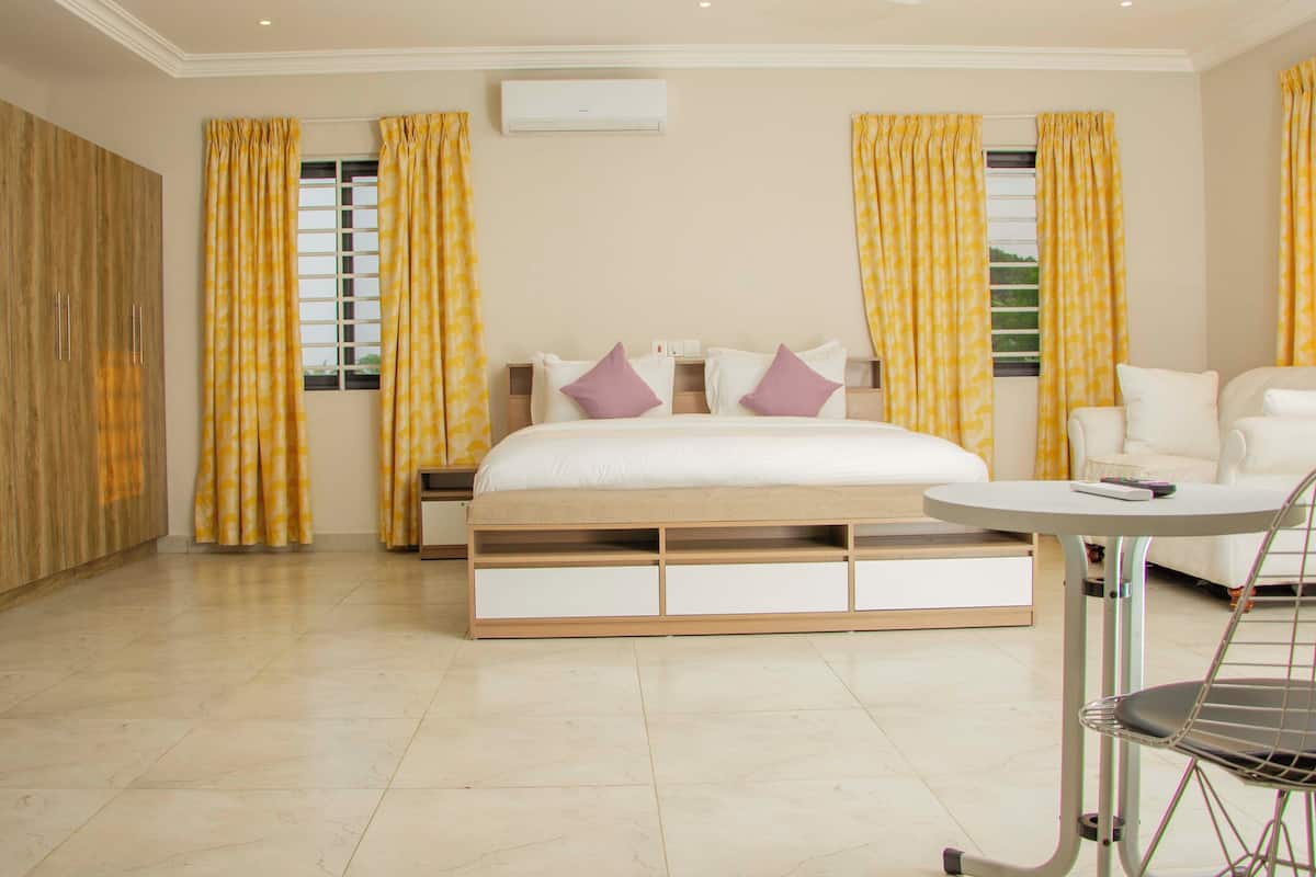 A bedroom with a bed, bedside tables, a chair, and curtains.