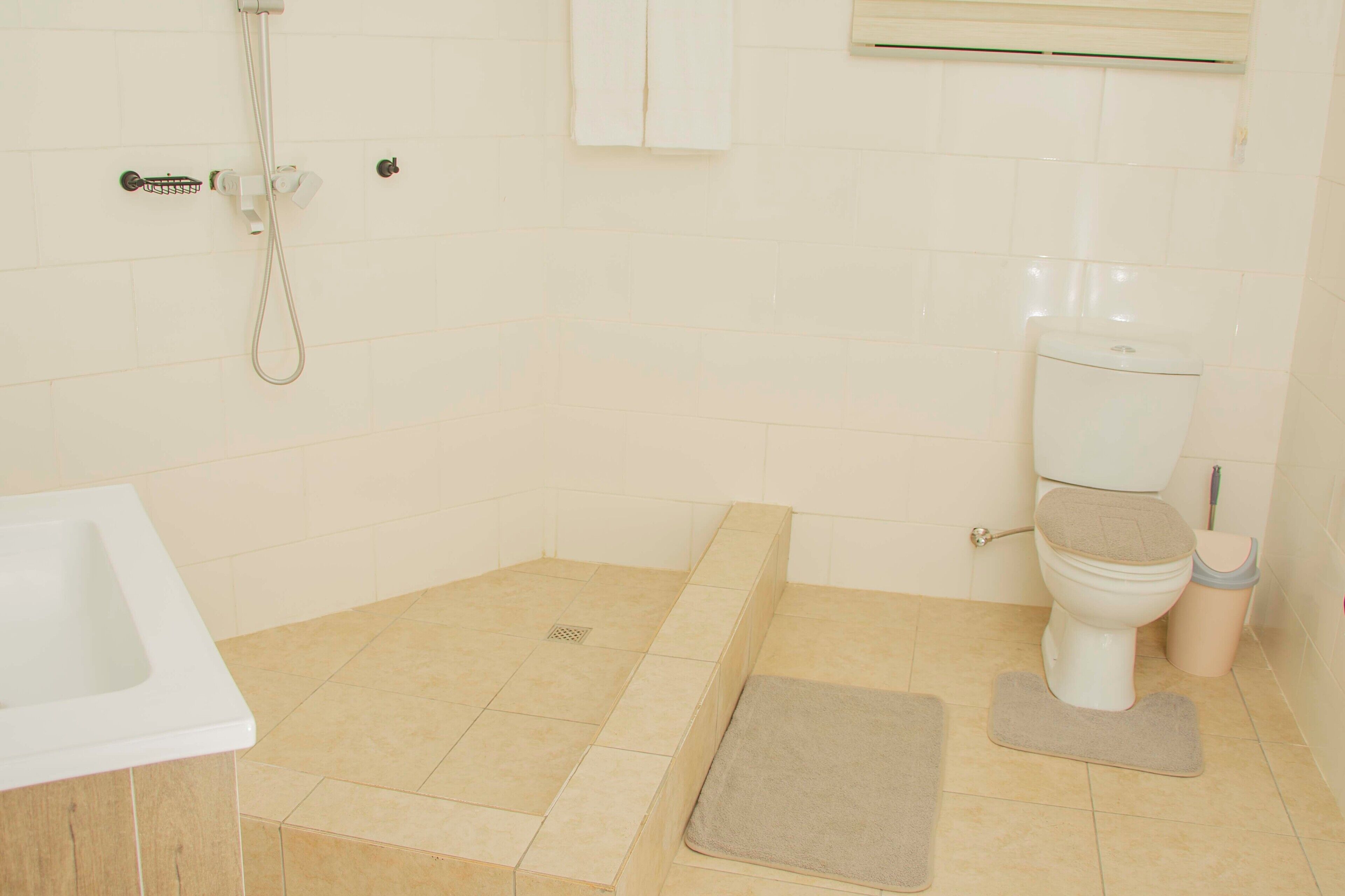 A bathroom with a toilet, a shower, and a sink.
