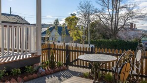 Ein Patio mit einem runden Tisch und Stühlen, umgeben von einem Holzzaun und einem weißen Zaun.