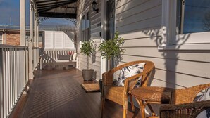 A covered porch with wicker furniture and potted plants.