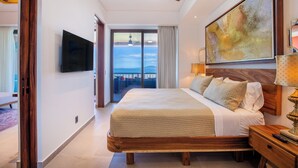 A spacious bedroom with a large bed, a ceiling fan, a mounted TV, and a balcony with a view. - Rooftop Pool + BBQ Terrace | Luxury Ocean View 2BR (Puerto Vallarta)