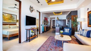 A spacious living area with a sofa, coffee table, and a large rug. There is a television mounted on the wall and a ceiling fan. - Rooftop Pool + BBQ Terrace | Luxury Ocean View 2BR (Puerto Vallarta)