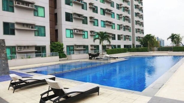 A modern building with a swimming pool, lounge chairs, and a palm tree. - Lovely 1-bedroom condo in fabulous Makati with WiFi, AC, fitness room (Makati)