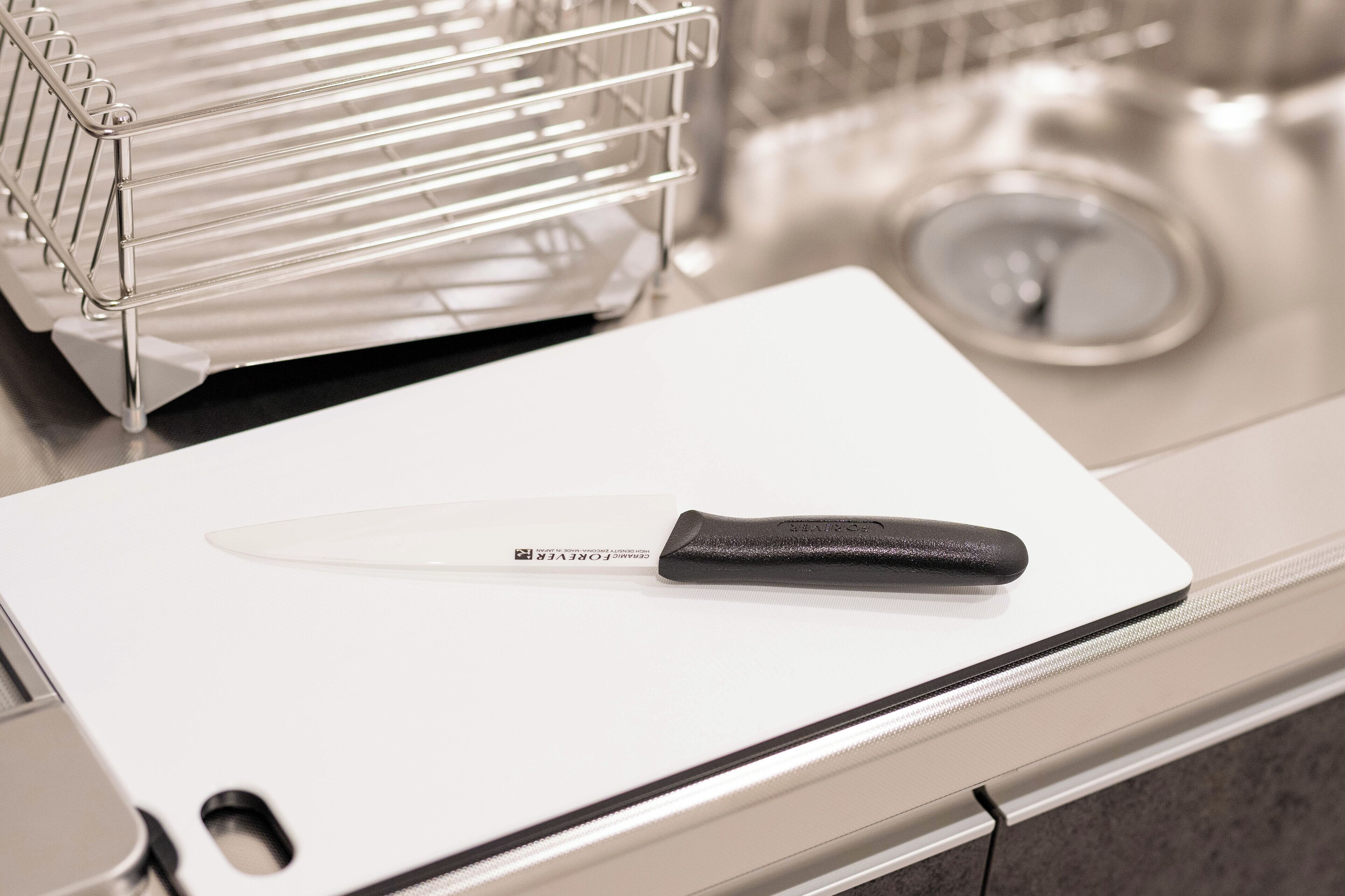 A kitchen counter with a white cutting board and a knife.