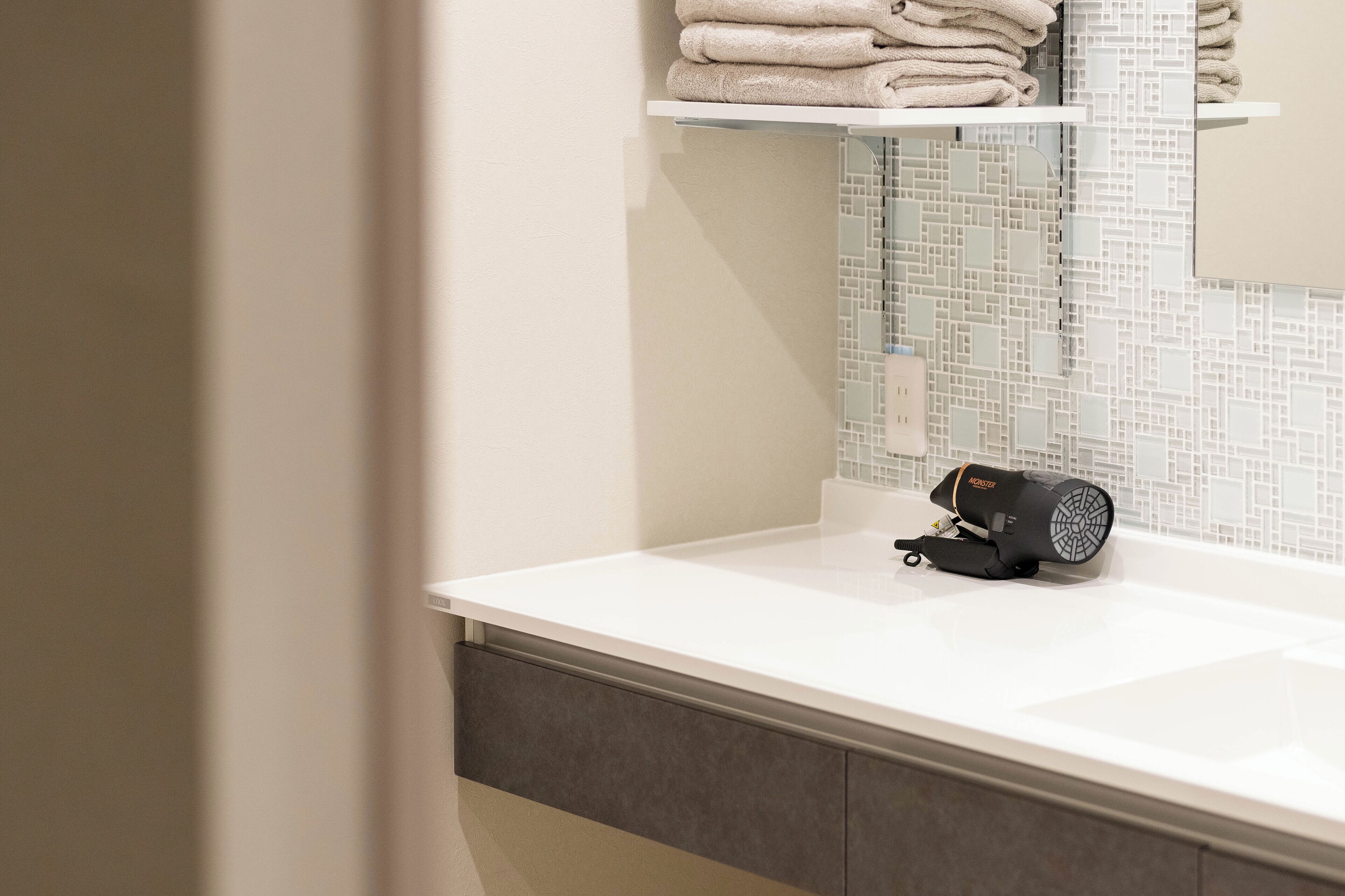 A bathroom with a white sink, a towel rack with folded towels, and a hairdryer on the counter.