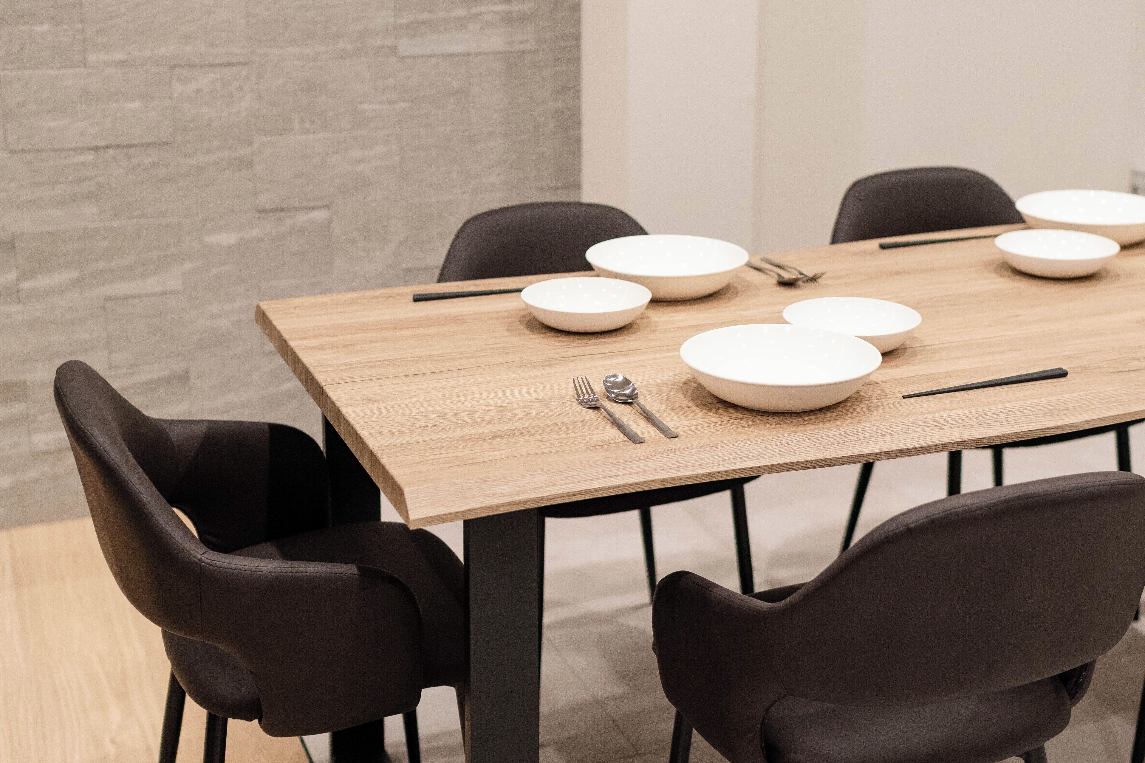 A dining table with four chairs, white plates, cutlery, and a black napkin.