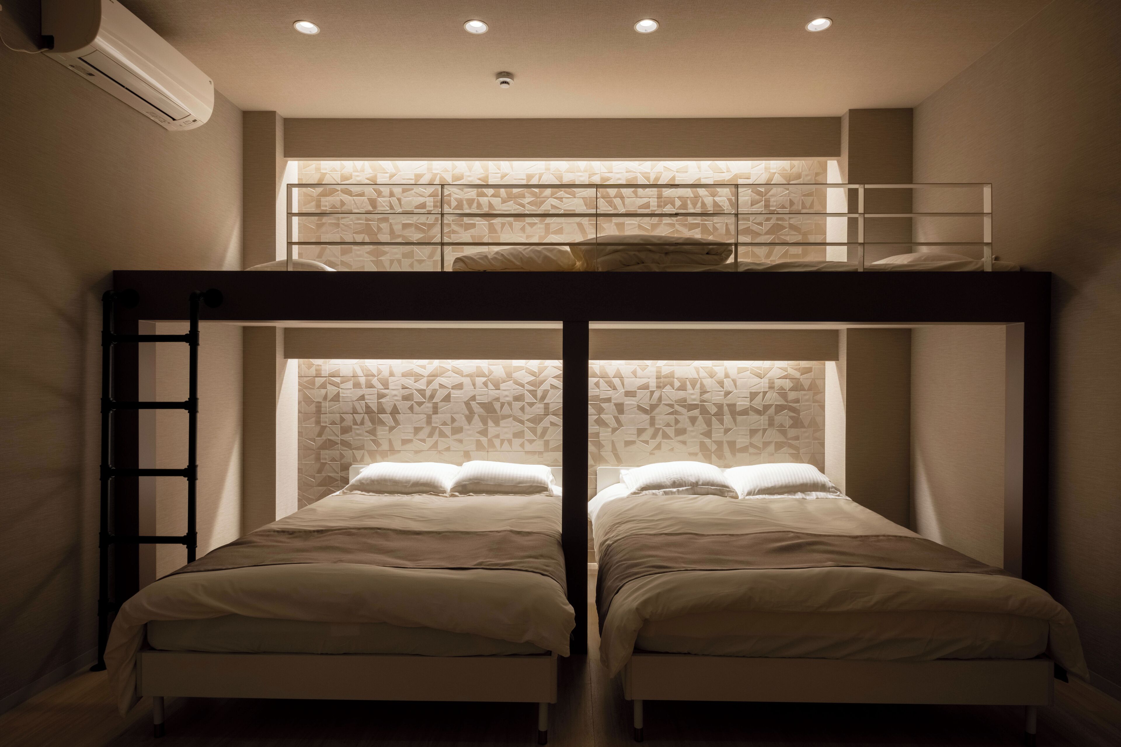 A bunk bed room with two beds, a ladder, and a geometric-patterned wall.