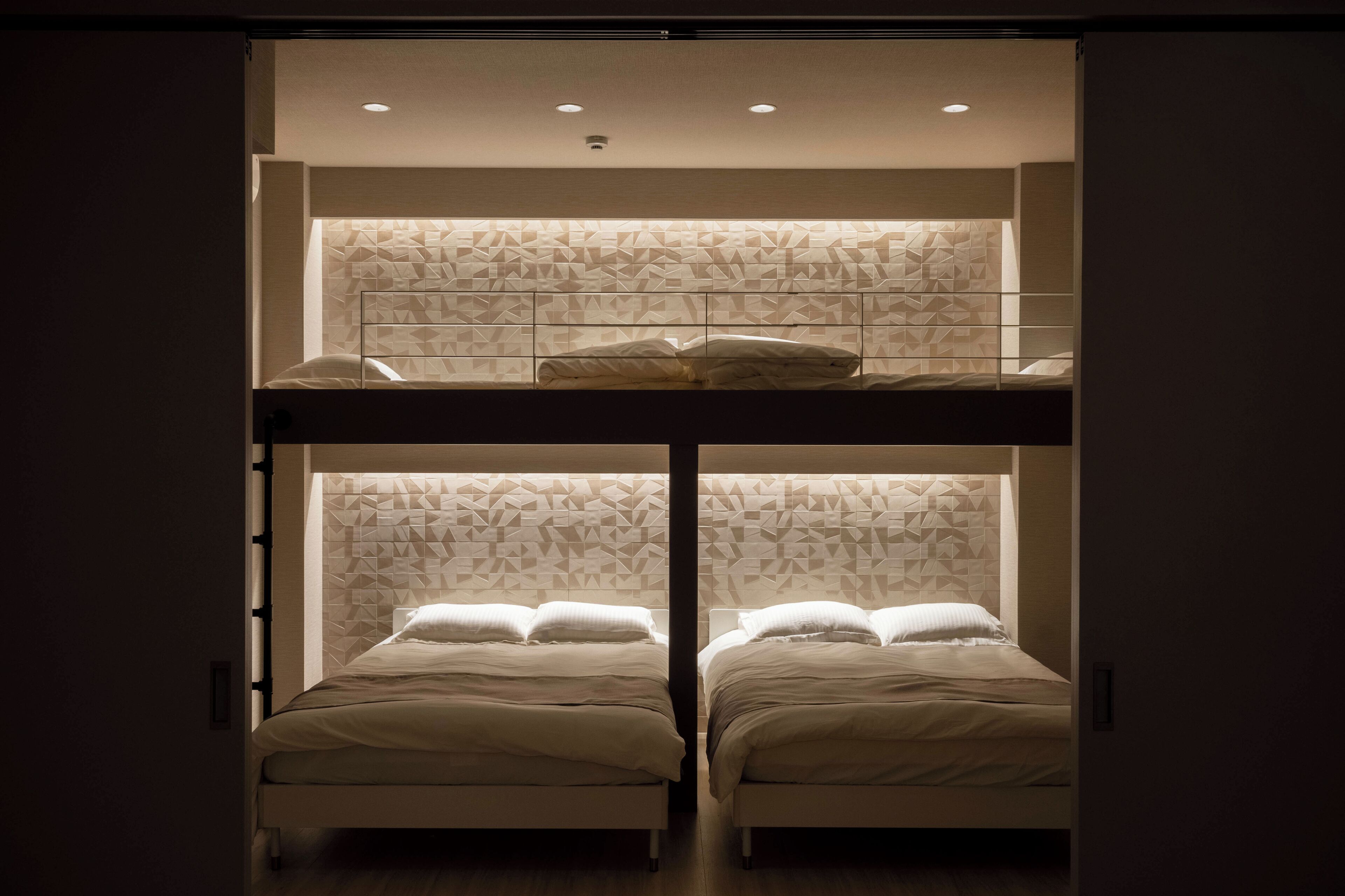 Een kamer met twee stapelbedden en een hoofdeinde met een geometrisch patroon.