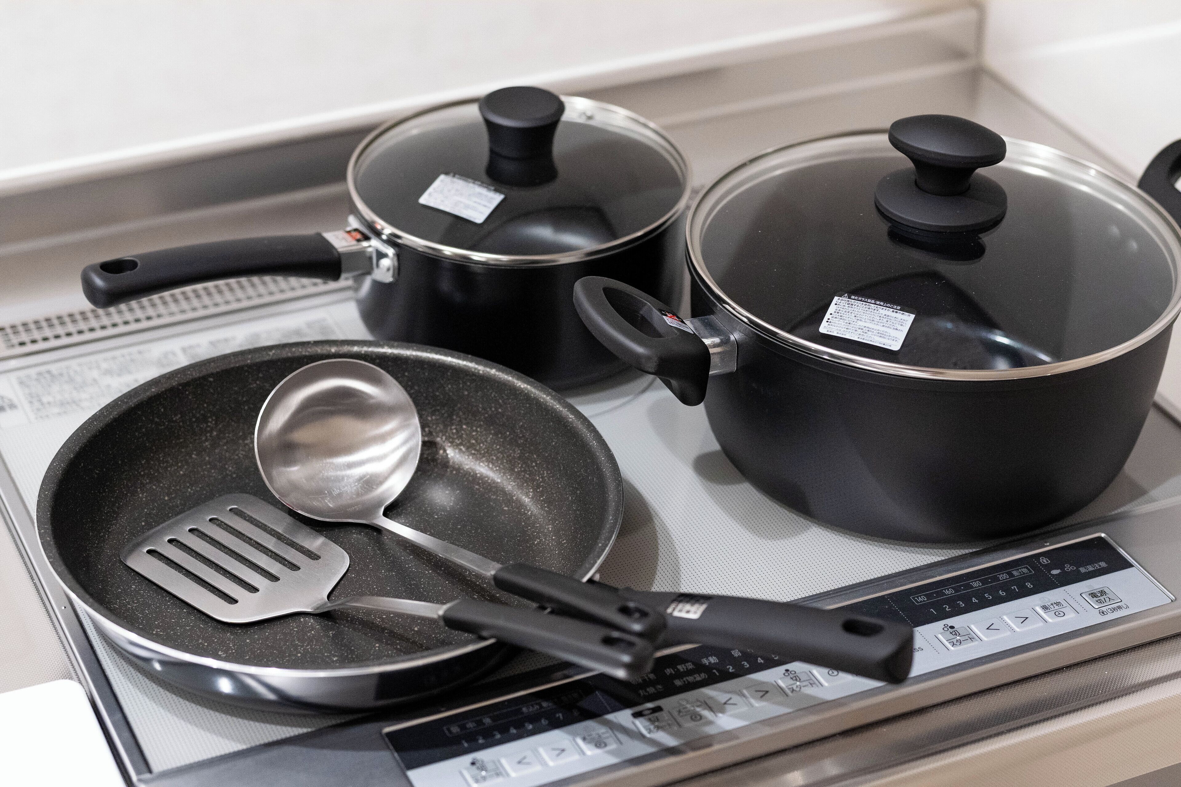A kitchen with a stove, pots, pans, and a digital control panel.