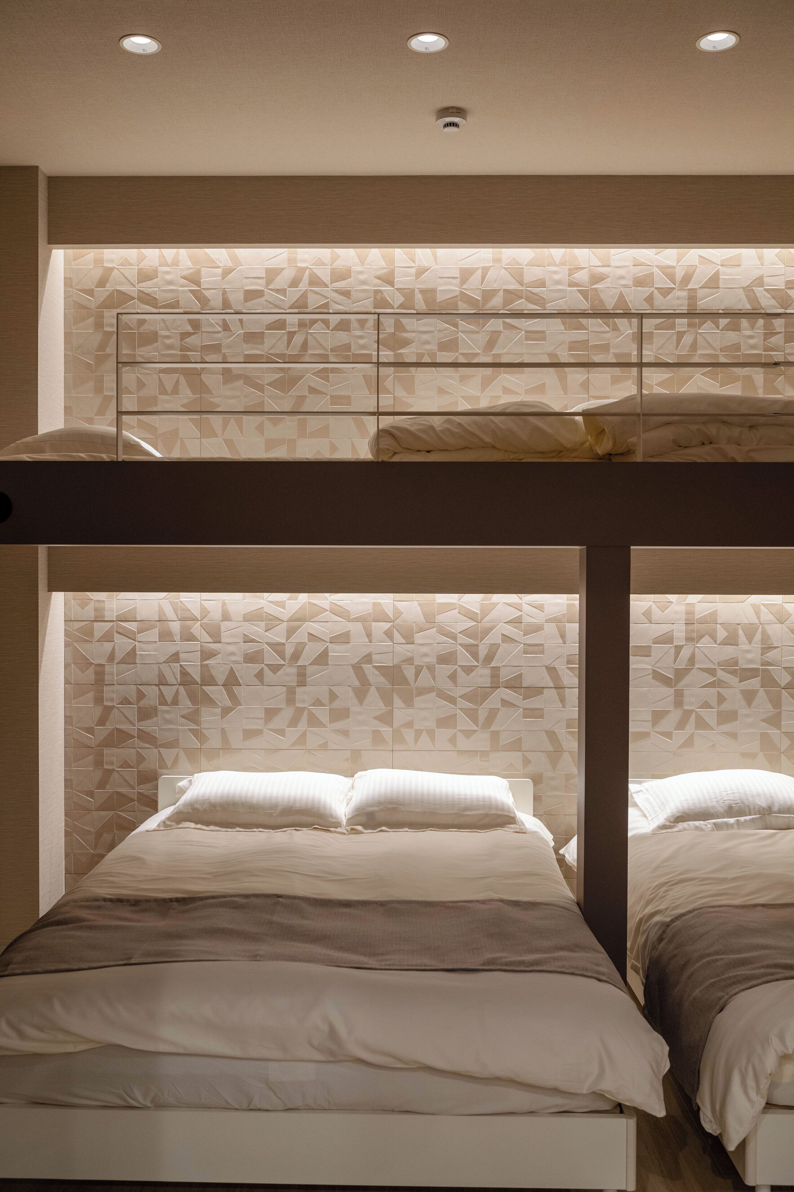 A bunk bed room with a geometric patterned headboard and a ceiling light fixture.
