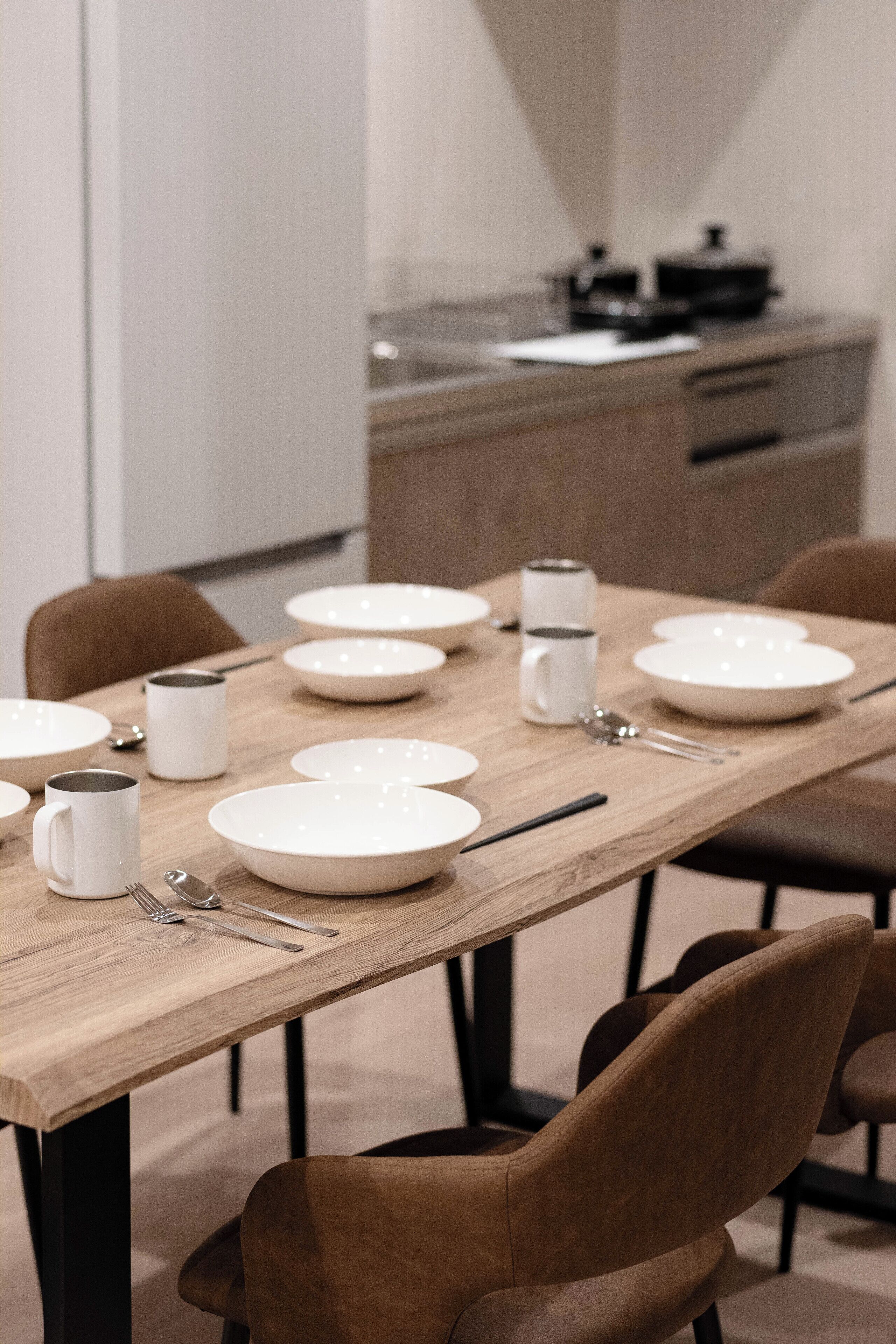 A dining table set with plates, bowls, and utensils, surrounded by chairs.