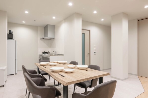 A modern dining area with a wooden table, eight chairs, and white bowls.