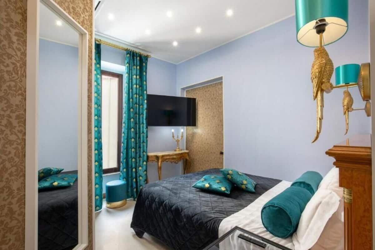 A bedroom with a bed, a TV, a mirror, and a lamp.