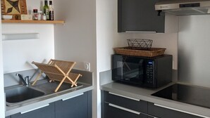 A modern kitchen with dark cabinets, a microwave, and a sink. - Appartement au Calme 10 mn à Pied Centre Ville (La Rochelle)