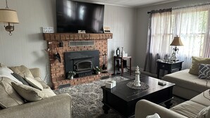 Una sala de estar con chimenea, televisor y sofá.