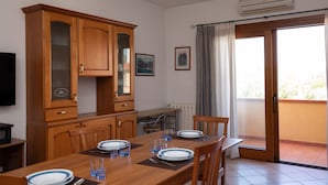 A dining area with a wooden table set for two, a cabinet, and a television on the left. - Casa delle Vigne by Wonderful Italy (Olbia)