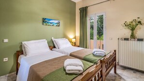 Habitación de hotel con dos camas, un cuadro en la pared, una ventana con cortinas y un radiador.