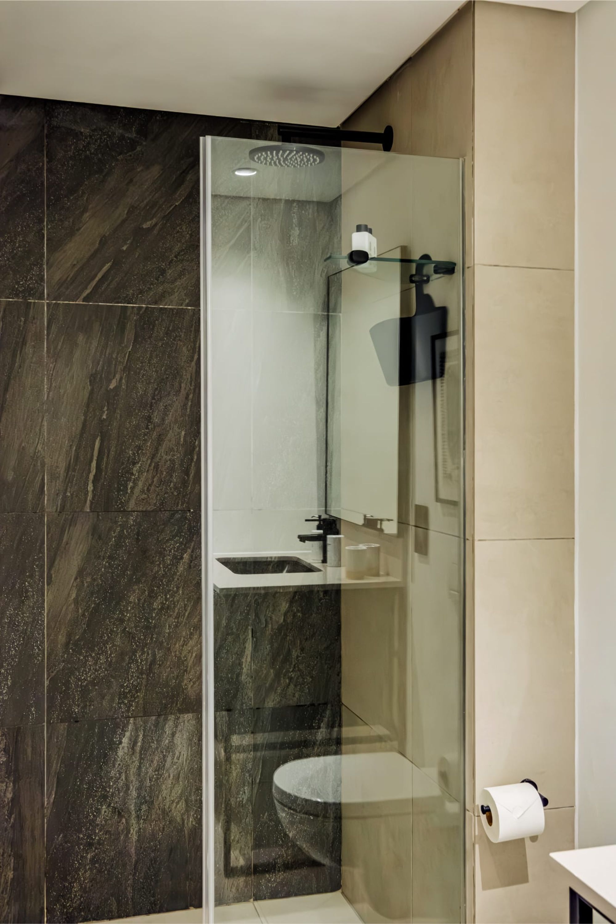 Een moderne badkamer met een douchecabine van glas, een toilet en een wastafel.