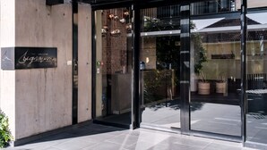 A modern building entrance with a glass door, a sign reading "The Signature," and a brick wall. - Contemporary Charming Apartment The Urban Edge (Cape Town)