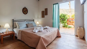 A bedroom with a bed, bedside tables, and a view of the outdoors. - Summer Rose Garden Getaway - A Step to the Beach (Kalamata)
