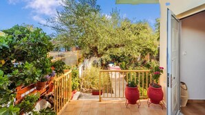 A balcony with a view of a garden, a gate, and a door to a room. - Summer Rose Garden Getaway - A Step to the Beach (Kalamata)