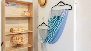 A wooden shelf with a 'No Smoking' sign, a wicker lamp, a floral box, and a patterned garment hanging on a wall. - Summer Rose Garden Getaway - A Step to the Beach (Kalamata)
