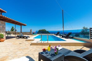 A pool area with lounge chairs and a table with drinks, overlooking a scenic view. - Escape to Paradise - Chania s Seaside Getaway (Platanias)