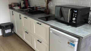 Una cocina moderna con armarios blancos, microondas y lavavajillas.