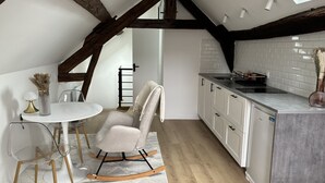 Una cocina moderna con armarios blancos, encimera gris y suelo de madera.