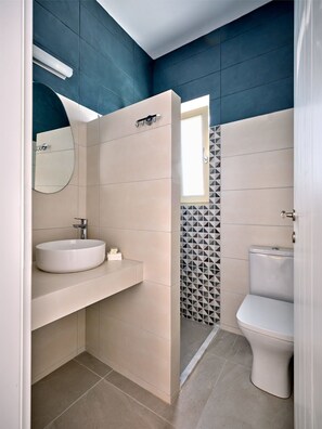 A modern bathroom with a white sink, a mirror, and a toilet.