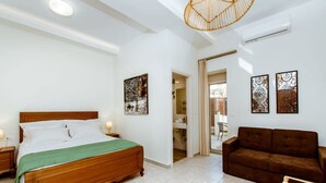 A bedroom with a wooden bed, a brown sofa, and two wall-mounted artworks. - Chania Paradise Retreat-falasarna Villa Nostalgia (Kissamos)
