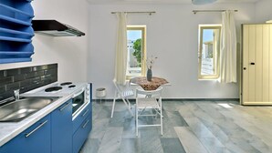 Una cocina moderna con armarios azules, una estufa a gas y una silla blanca junto a una mesita.
