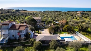 Una propiedad costera con piscina, cancha de tenis y vista al mar.